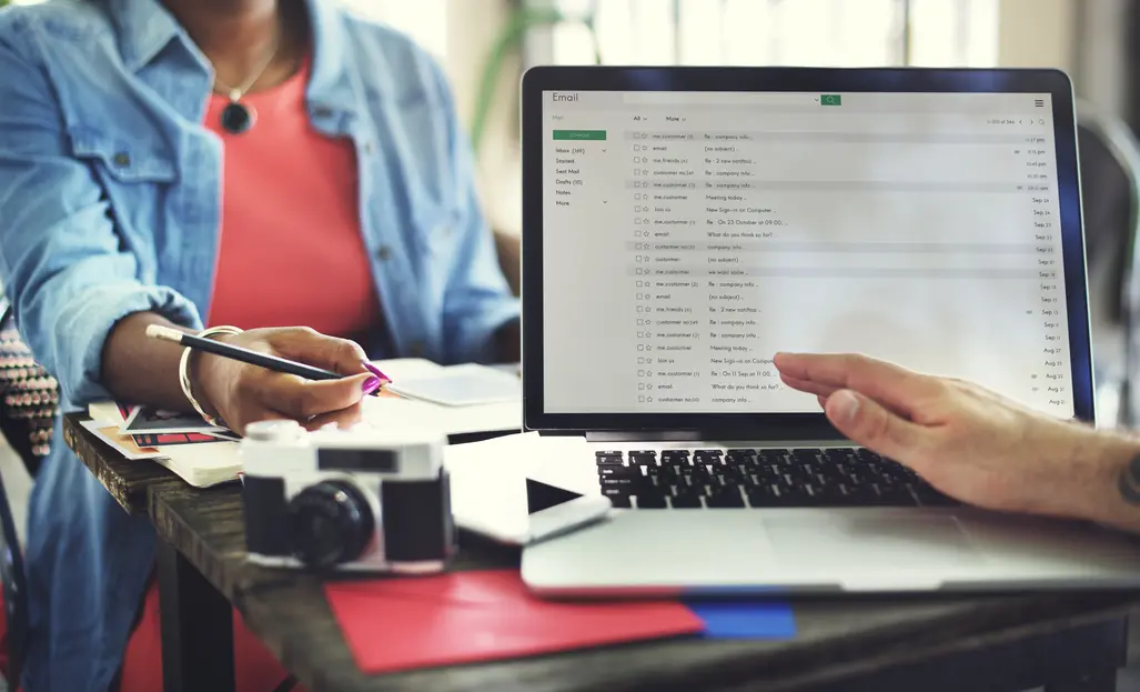 In einem modernen Büro-Setting arbeiten Marketing-Profis an einem datenschutzkonformen Setup für die E-Mail-Automatisierung. Auf einem Laptop ist eine E-Mail-Plattform geöffnet, auf der verschiedene E-Mails in einem Posteingang angezeigt werden. Im Vordergrund wird ein Notizbuch und ein Kameragerät sichtbar, während eine Person mit einem Bleistift Notizen macht. Der Fokus liegt auf der Integration von Künstlicher Intelligenz in E-Mail-Marketingstrategien, wobei der Prozess der Datenverarbeitung und der Einrichtung von Workflows hervorgehoben wird. Diese Arbeitsweise ist entscheidend für die effektive Umsetzung von E-Mail-Kampagnen unter Berücksichtigung von Datenschutzvorschriften wie der DSGVO, um die Skepsis gegenüber KI-Technologien im Marketing zu verringern. Die Szene vermittelt eine praxisorientierte Herangehensweise an die Herausforderungen im Marketing und zeigt, wie KI und Automatisierung zusammenarbeiten können, um die Effizienz und Effektivität von Kommunikationsstrategien zu steigern.