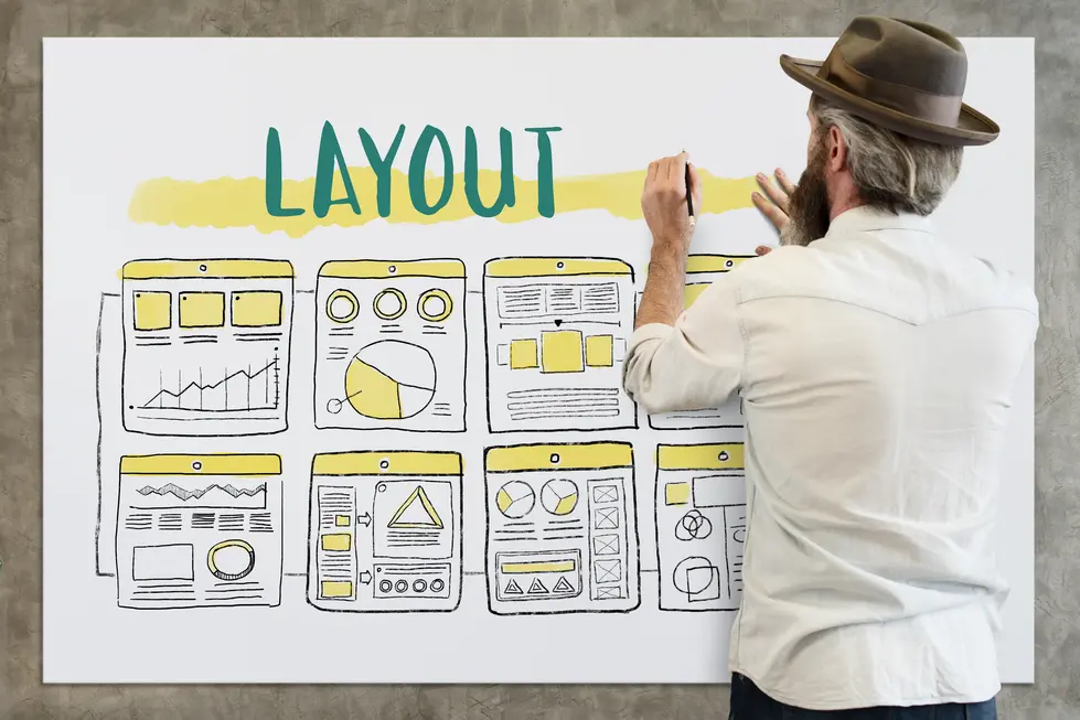 Ein Mann mit einem Hut zeichnet auf ein großes Plakat, das verschiedene Website-Layouts zeigt. Auf dem Plakat sind mehrere skizzierte Webseiten mit Diagrammen, Grafiken und Textabschnitten abgebildet, während der Mann den Schriftzug "LAYOUT" in leuchtendem Blau über die Zeichnungen aufträgt.