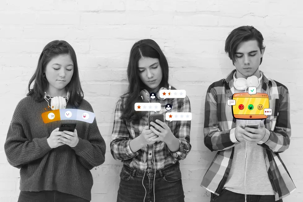 Drei junge Menschen stehen nebeneinander und nutzen ihre Smartphones, während sie in einem minimalistischen Raum vor einer weißen Backsteinwand stehen. Sie tragen Kopfhörer und haben unterschiedliche Trauermuster auf ihren Handys, die Symbolik für Emotionen und Meinungen darstellen. Die Person links zeigt eine negative Emotion, während die mittlere Person einen neutralen Gesichtsausdruck hat, und die Person rechts eine positive Rückmeldung erhält. Digitale Elemente in Form von Bewertungen und Kommentaren erscheinen über ihren Handys, was die Interaktion mit sozialen Medien und die emotionale Reaktion auf Inhalte verdeutlicht.