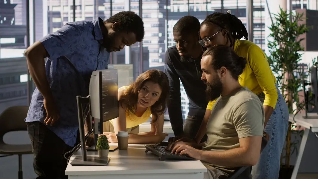 Entwicklungsteam, das an der Optimierung einer Webseite arbeitet, während sie gemeinsam einen Computerbildschirm betrachten und strategische Entscheidungen zur Verbesserung der Website-Performance treffen.