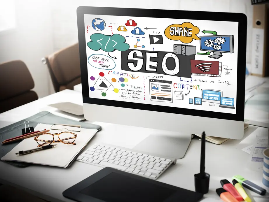 Computer-Bildschirm zeigt eine Übersicht über SEO-Content-Marketing-Strategien, einschließlich Grafiken und Texten zu Kreativität, Layout, Inhalten, Teilen und Prozessen. Auf dem Tisch liegen eine Brille, Stifte, Notizen und ein Tablet. Das Bild vermittelt eine kreative und analytische Arbeitsumgebung für digitales Marketing.