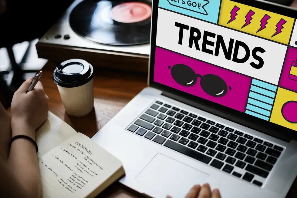 Moderne Webdesign-Trends 2025: Mit einem Fokus auf emotionale Gestaltung und messbare Performance zeigt dieses Bild einen Laptop, auf dem das Wort "TRENDS" in auffälliger Typografie präsentiert wird. Umgeben von kreativen Elementen und einem künstlerischen Layout, symbolisiert das Design den Paradigmenwechsel zu ausdrucksstärkeren und emotionaleren Konzepten. Neben dem Laptop ist eine Kaffeetasse platziert, während eine Person Notizen macht, was den kreativen Prozess unterstreicht. Im Hintergrund ist ein Plattenspieler zu sehen, der eine Verbindung zur Nostalgie und einem innovativen Lebensstil herstellt. Dieses Bild spiegelt die zukünftige Balance zwischen künstlerischem Ausdruck und technischer Funktionalität wider, was für Webdesigns 2025 von zentraler Bedeutung ist.
