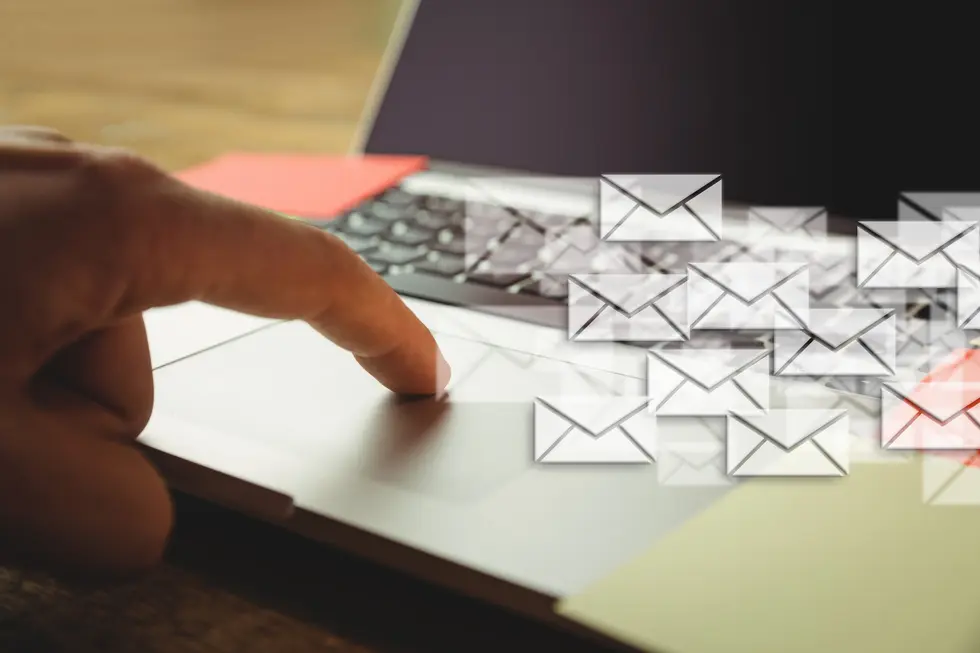 Finger drückt auf ein Laptop-Trackpad, während auf dem Bildschirm mehrere E-Mail-Symbole angezeigt werden, das Bild vermittelt die Idee von digitaler Kommunikation und E-Mail-Marketing. Ein inspirierendes Arbeitsumfeld mit einem klaren Fokus auf Technologie und Effizienz im modernen Büro.