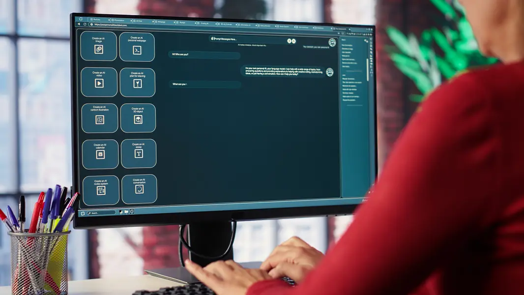 Benutzer interagiert mit einem KI-gestützten Dashboard auf einem Computerbildschirm, das Optionen zur Erstellung von AI-Inhalten bietet, darunter Videos, Webseiten, Kalender und Konversationen, während Schreibutensilien in einer Nähe stehen.
