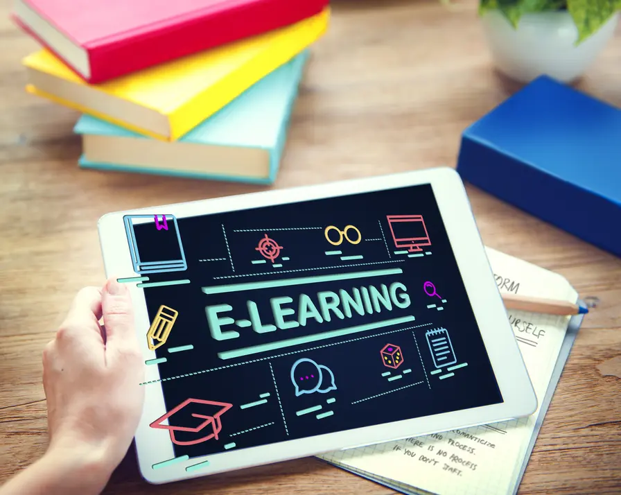 E-Learning auf einem Tablet, umgeben von bunten Lehrbüchern und einer Notizblock, der die digitale Lernumgebung symbolisiert. Die Darstellung umfasst verschiedene Icons, die mit Online-Lernen assoziiert werden, wie ein Buch, eine Brille und ein Computer. Diese Szene verdeutlicht die moderne Bildungslandschaft, in der Technologien und digitale Ressourcen die Art und Weise des Lernens transformieren.